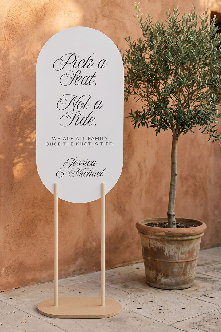 Oval pick a seat sign beside an olive tree and terracotta wall #shape_Oval#size_Signature