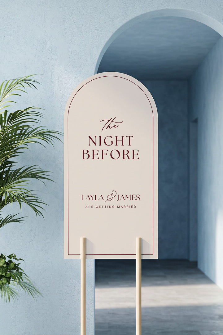Linen off white arch rehearsal dinner sign leaning in a blue plaster archway beside a potted palm #color_Linen