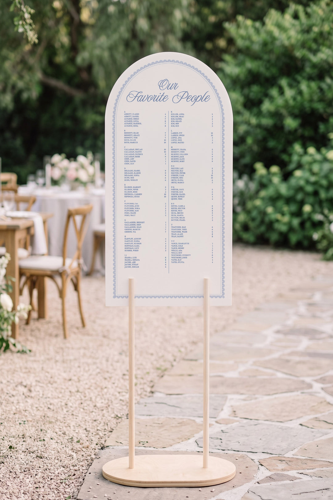 Powder blue arch wedding seating chart with a lace border, guests listed A to Z with table numbers #shape_Arch#color_Powder