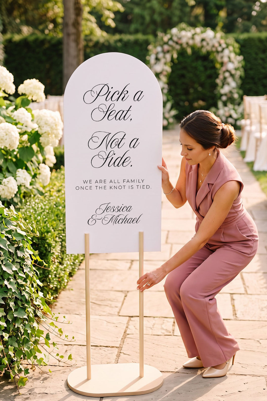 Stylist setting up the arch pick a seat sign in a hydrangea garden #shape_Arch#size_Signature