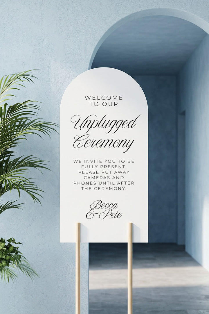 Arch unplugged ceremony sign on a wood stand in a blue arched alcove #shape_Arch#size_Signature