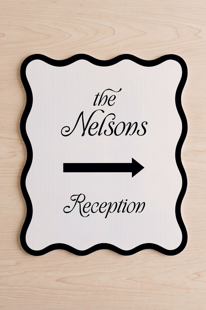 Black wavy wedding directional sign shown flat, family name above the arrow #Color_Black