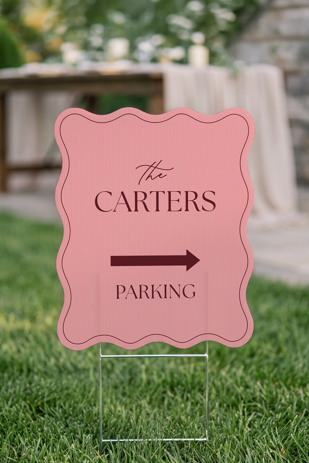 Rosé pink wavy wedding directional yard sign staked in a lawn in front of a stone wall #Color_Rosé