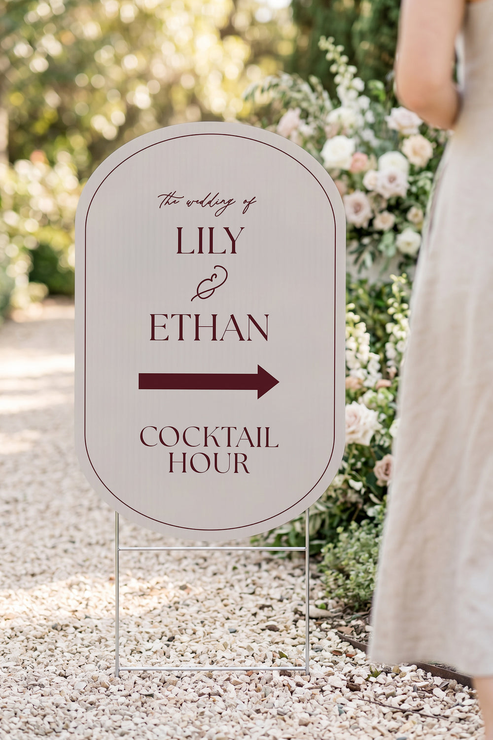 Linen off white pill wedding directional yard sign in a garden beside a flower arch #Color_Linen