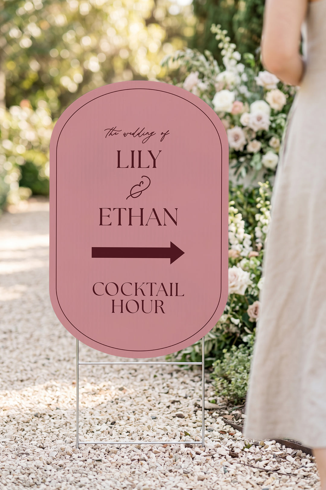 Rosé pink pill wedding directional yard sign in a garden beside a flower arch #Color_Rosé