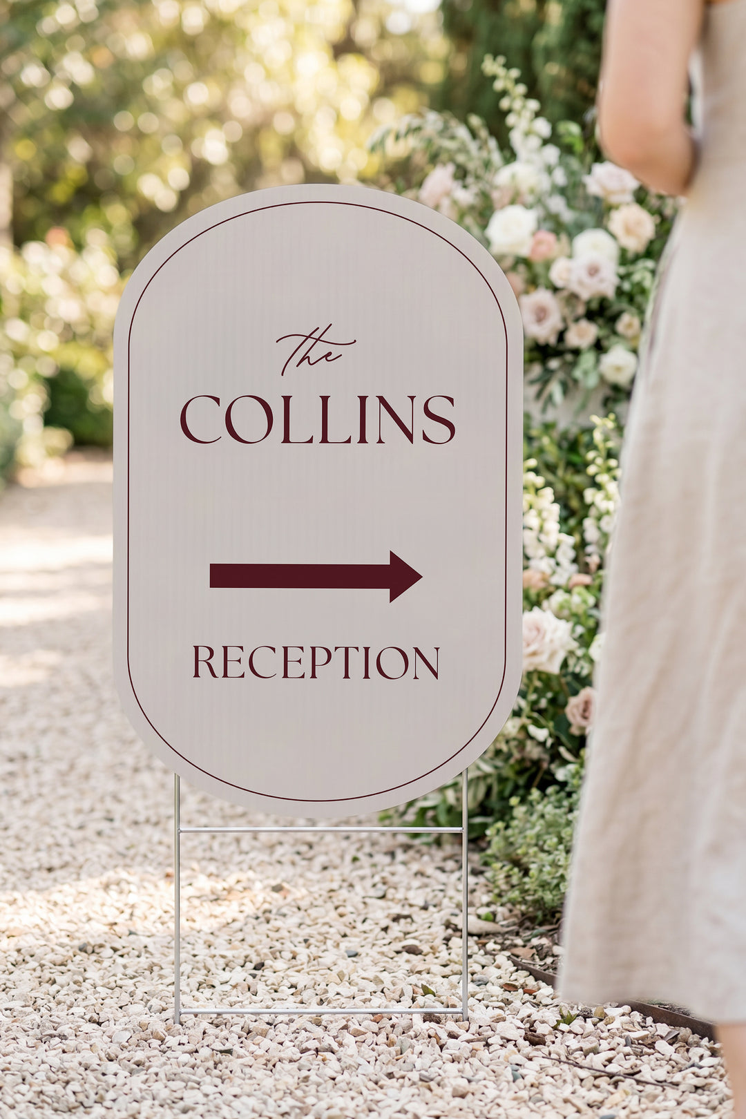 Linen off white pill wedding directional yard sign in a garden beside a flower arch #Color_Linen