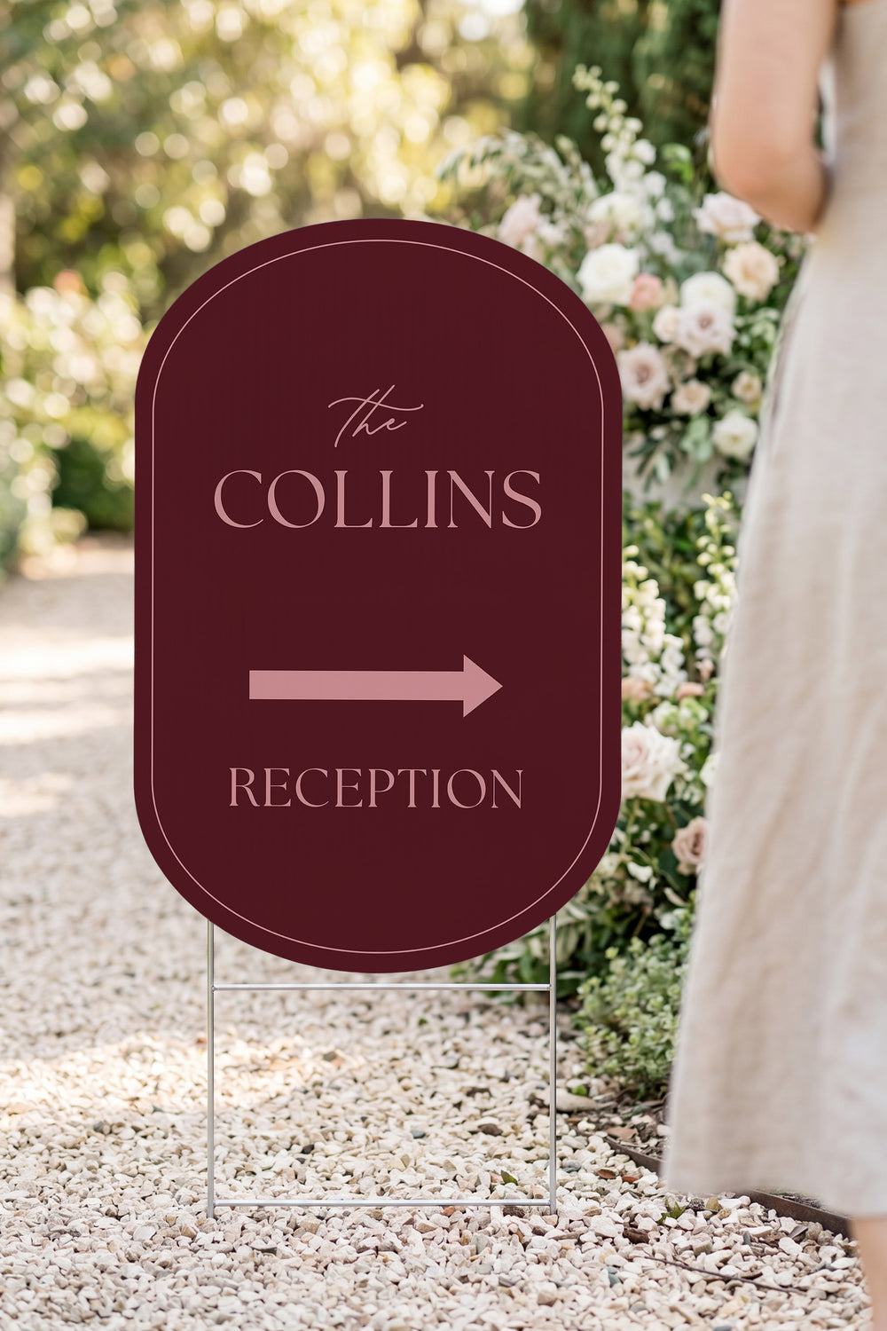 Merlot pill wedding directional yard sign in a garden beside a flower arch #Color_Merlot