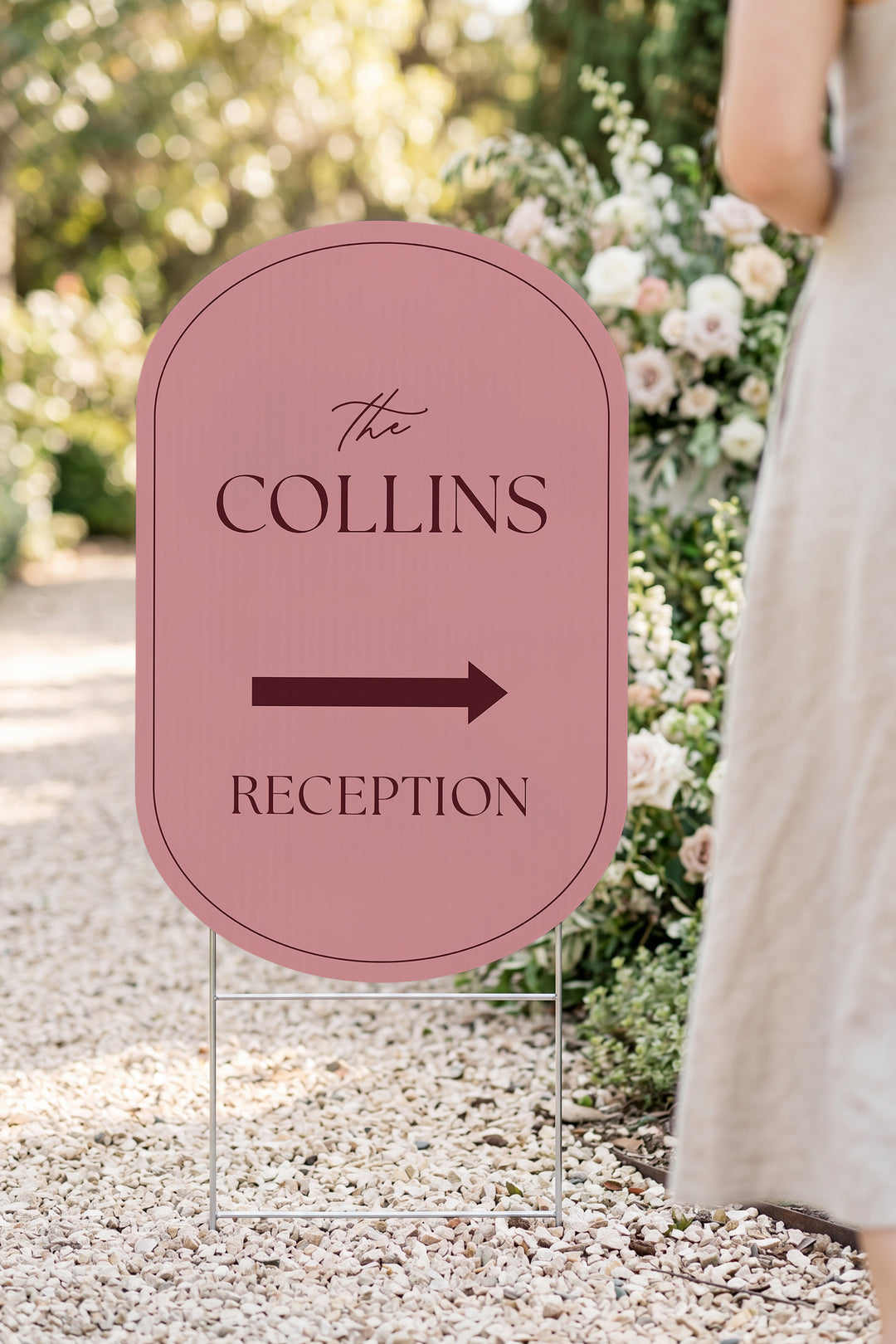 Rosé pink pill wedding directional yard sign in a garden beside a flower arch #Color_Rosé